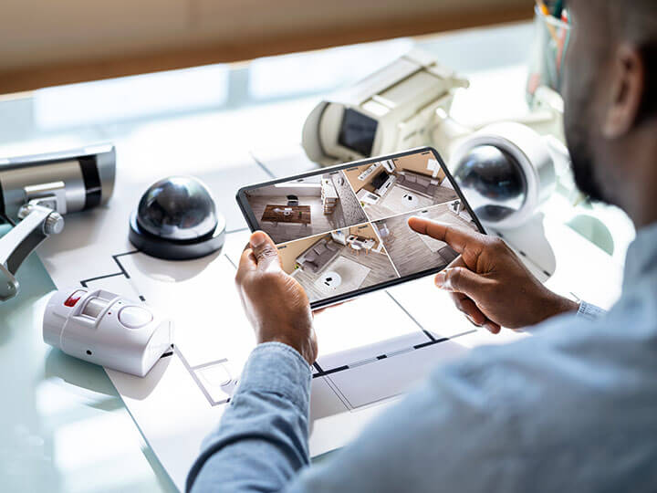 Adult male looking at security camera video on table with alarms and fire surveillance equipment on the desk